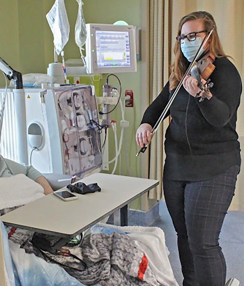 Photo of ICMH’s newest physician, Dr. Bhreagh MacDougall, volunteering to play a selection of tunes for a patient